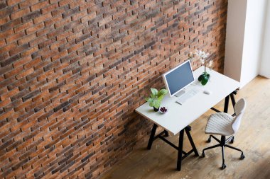 Workspace with computer on the table near brown brick wall, copy space