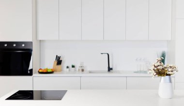 Modern stylish white kitchen with white walls, black oven and stove, copy space