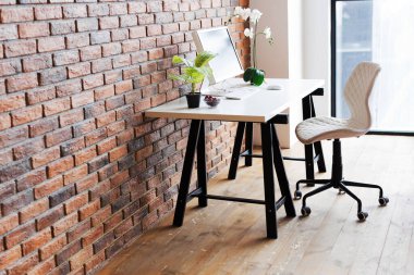 Workspace with computer on the table near brown brick wall, copy space