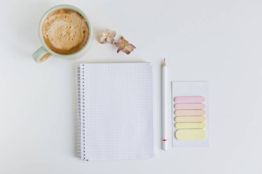 Flat lay with empty open notebook, cup with coffee and sticky post it on a white background, copy space