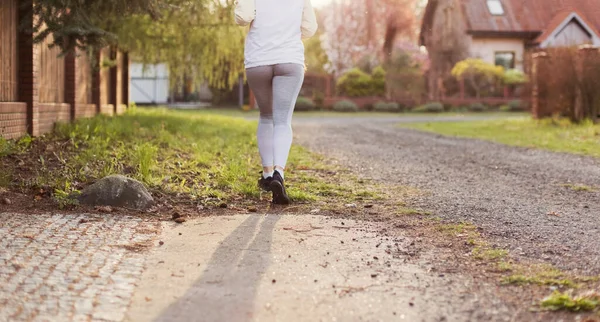 stock image Running woman outdoors at sunlight. Banner with summer village street with running woman on background