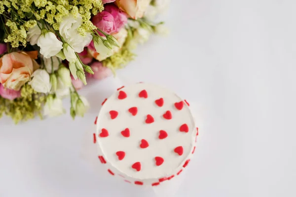 Białe Ciasto Czerwonymi Sercami Dekoracji Bukiet Jasnych Kwiatów Białym Tle — Zdjęcie stockowe