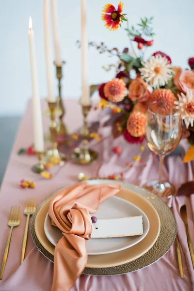 漂亮的餐桌布置 秋天的花朵 橙色和粉红色的餐巾和燃烧的蜡烛 秋季婚礼的概念 免版税图库照片