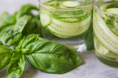 Taze yeşil sebze kokteyli. Fesleğenli moktail ve salatalık. Gri arka planda yeşil taze içecek.