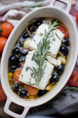Fırında makarna peyniri, domates, zeytin, sarımsak, yağ, bal ve biberiye.
