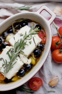 Fırında makarna peyniri, domates, zeytin, sarımsak, yağ, bal ve biberiye.