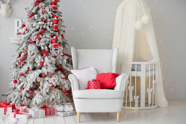 圣诞树上有红色装饰 白色扶手椅上有垫子 婴儿床上有天篷 在可爱的儿童房里有灰色墙壁 — 图库照片