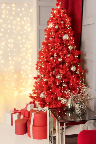金色の装飾が施された赤いクリスマスツリーと ボケのクリスマスライトを背景にリボンが付いたギフトボックス — ストック写真
