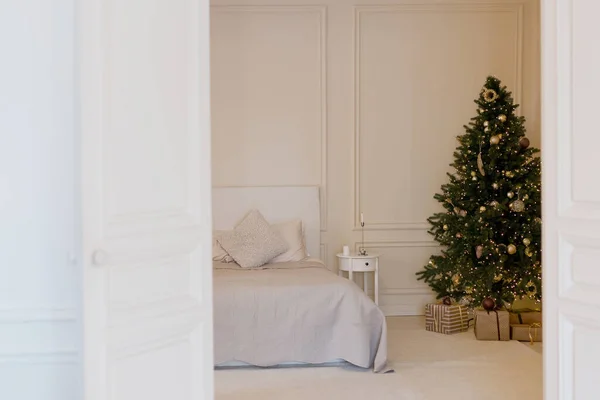 有圣诞树的明亮的圣诞卧室 床与米黄色我白色的枕头 垫子和毛毯靠近圣诞树 免版税图库照片