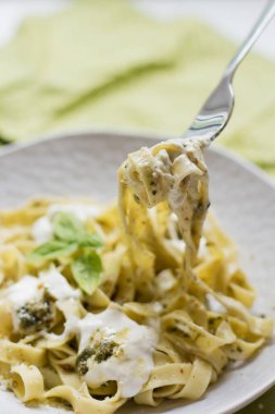 Pesto soslu ev yapımı tagliatelle makarna ve tabakta stracciatella di bufala peyniri.