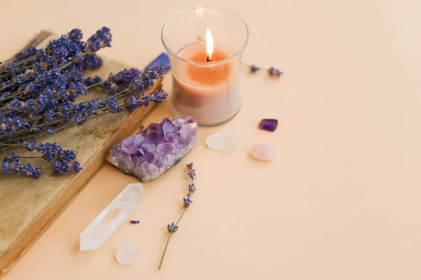 紫水晶 天然宝石 点燃的蜡烛和淡淡的背景下的薰衣草花朵 复制空间 图库图片