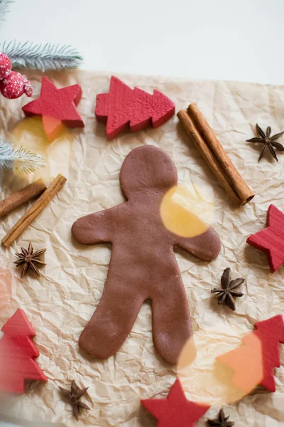 Gingerbread man on baking paper background with cinnamon sticks and star anise. Making christmas cookies concept