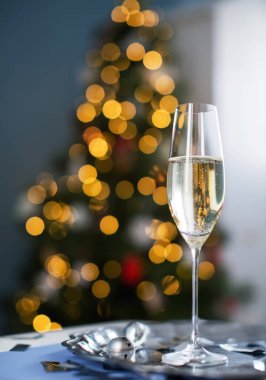 Bir bardak şampanya, Noel çanları, yanan maytaplar ve yılbaşı ağacında gümüş konfeti olan klasik gümüş tepsi.