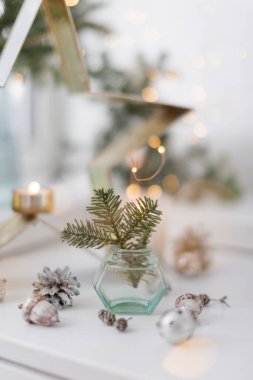 Bouquet of green spruce branches in vase, white burning candles and star decoration at home interior