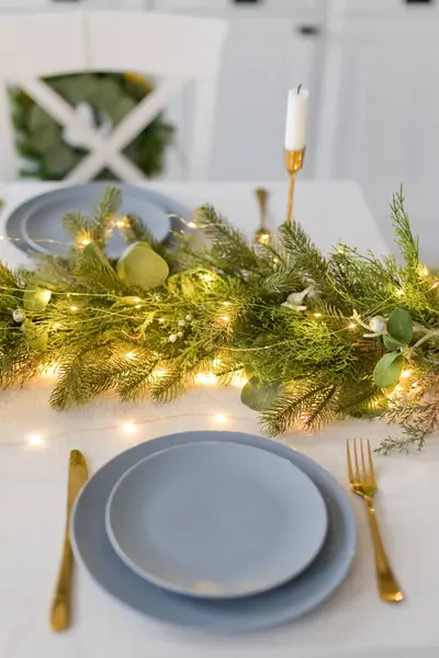 Table with Christmas decor and plate. Christmas table setting, cozy holiday dinner