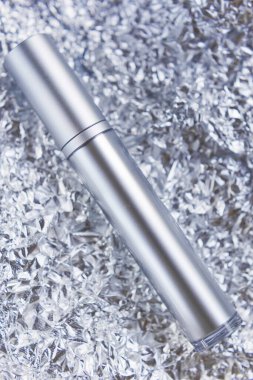 Folyo arka plan modelinde gümüş kozmetik şişe