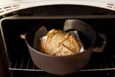 Fırındaki dökme demir tencerede taze pişmiş ekşi ekmek.