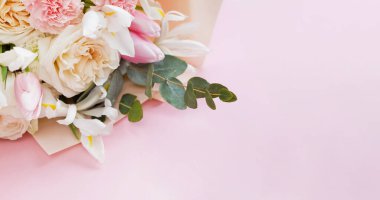 Beautiful bouquet with roses, carnations, iris and eucalyptus on a pink background, copy space. Mothers day, 8 march, holiday gift concept