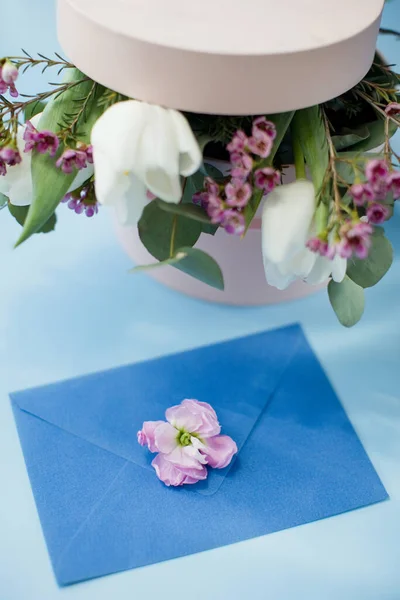 Blue envelope and pink gift box with bouquet on a blue background