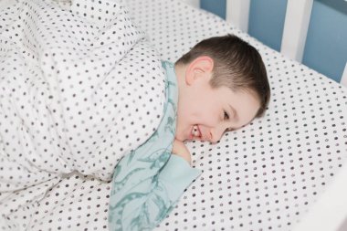 Mavi pijamalı, yatakta yatan Kafkasyalı öğrenci.