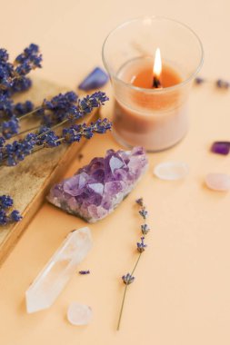 Ametist, doğal değerli taşlar, yanan mum ve lavanta çiçekleri.
