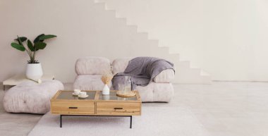 Bright interior with sofa, wooden table, plant and stairs