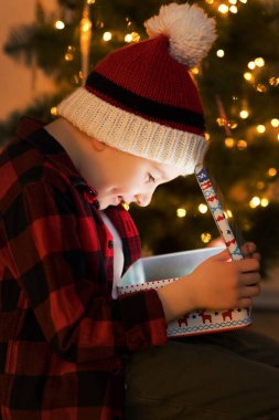 Örgü şapkalı çocuk içinde sihirli ışık olan Noel hediyesini aç