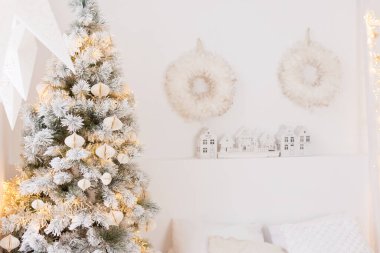 Kağıt süslemeli Noel ağacı ve beyaz yatak odasında rahat ışıklar.