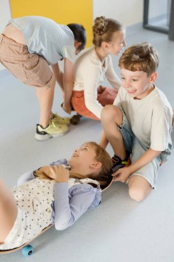 Okul koridorunda kaykaylı mutlu çocuklar, eğleniyorlar.