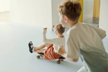 Okul koridorunda kaykaylı mutlu çocuklar, eğleniyorlar.