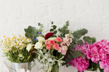 Beyaz tuğla duvarın yanındaki vazolarda çiçekler