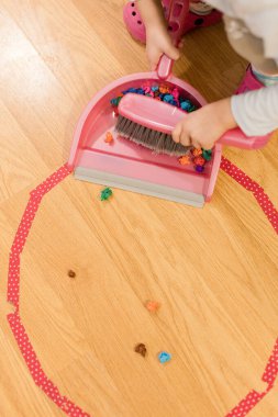 Çocuk, Montessori etkinliğinde pembe bir faraş ile süpürme alıştırması yapıyor.
