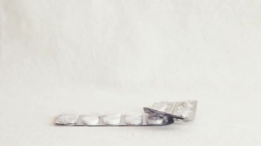 Medicine blister pack falling one by one from top frame and piling up on white background in normal view