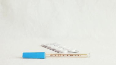 Tıbbi su toplayıcı beyaz arka planda kişisel termometrenin üzerine düşüyor