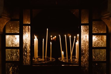 Yellow bright candles behind glasss, covered with wax