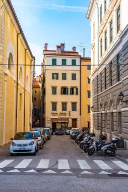 Trieste, İtalya - 21 Ağustos 2019 - Şehrin orta kesiminde park edilmiş araçları ve küçük mağazası olan dar bir cadde