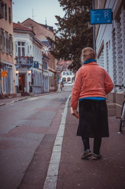 Heidelberg, Almanya - 26 Aralık 2018 - Yaşlı kadın elinde kitap asarak sokakta yürüyor