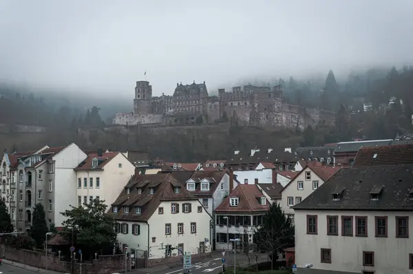 stock image Heidelberg, Germany - Dec 26, 2018 - couple of ancient houses in the central part of the city with a castle in the fog on the background