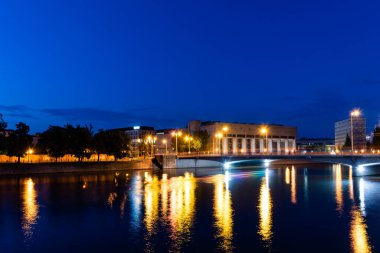 Gece şehrinin renkli ışıkları nehri yansıtıyor.