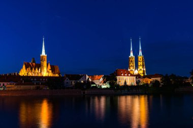 Gece şehrinin renkli ışıkları nehri yansıtıyor.