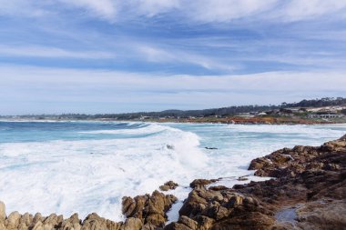 Okyanus suyundan gelen beyaz köpük kayalara çarpıyor.