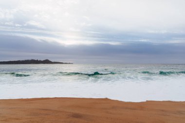 Okyanus suyundan gelen beyaz köpük kayalara çarpıyor.