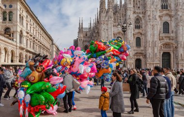 Milan, İtalya - Şubat 2023: Balon ve konfetiyle güneşli bir bahar gününde Milano 'daki Piazza Duomo Karnaval kutlamaları sırasında karnaval gibi giyinmiş kalabalık