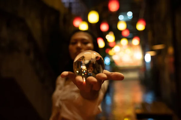 通りのクリスタル球を保持するアジアの女性の手に焦点を当てる — ストック写真