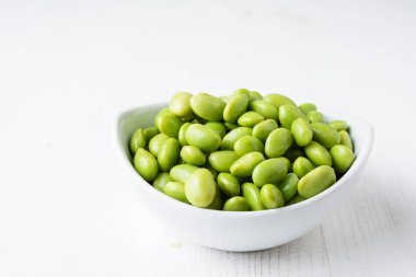 Beyaz kasedeki edamame taneciklerinin üst görüntüsü, beyaz masa üzerinde, yatay, kopyalama alanı ile