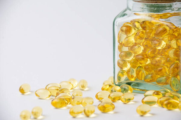 Вид на крытую стеклянную бутылку с вечерними таблетками масла первоцвета, на белом фоне с таблетками, горизонтальные, с копировальным пространством