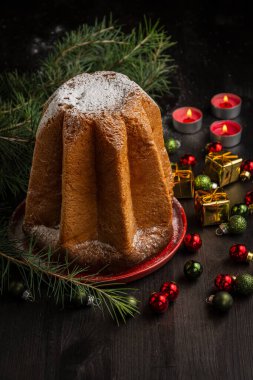 Pandoro pandoro pandoro kekinin en üst görüntüsü şeker, yeşil dallar, karanlık masa üzerinde mumlar ve Noel süslemeleri, siyah arka plan, dikey, kopyalama alanı ile