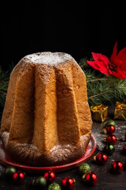 Pandoro pandoro kekinin en üst görüntüsü şekerli, yeşil dallı, koyu renkli, Noel süslemeli, siyah arka planlı, dikey, kopyalama alanı olan