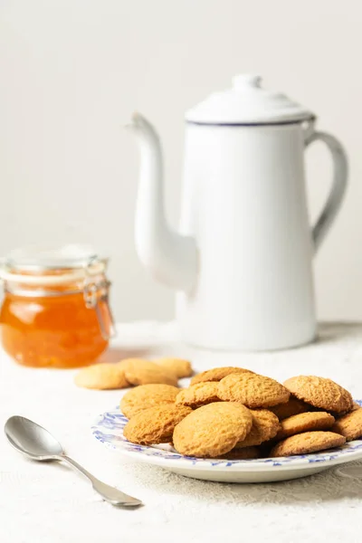 Top view of cookies, jam jar, spoon and old fashioned coffee pot on table with white tablecloth, selective focus, vertical, white background, with copy space