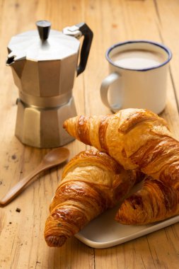 Top view of croissants on wooden table with coffee pot and cup with coffee, wooden background vertical